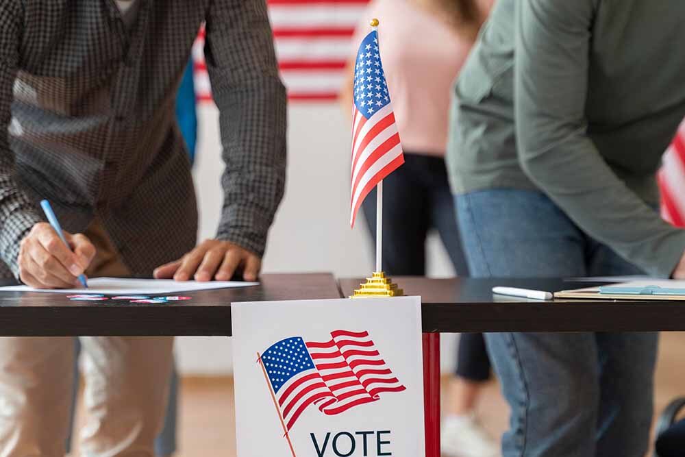 Poll workers stand behind a desk